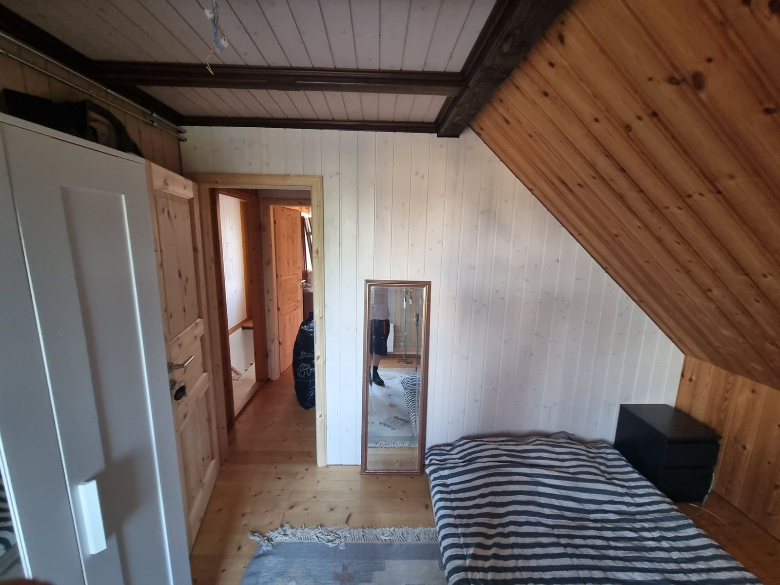 Dachzimmer mit weissem Täfer und Türe aus Fichtenholz